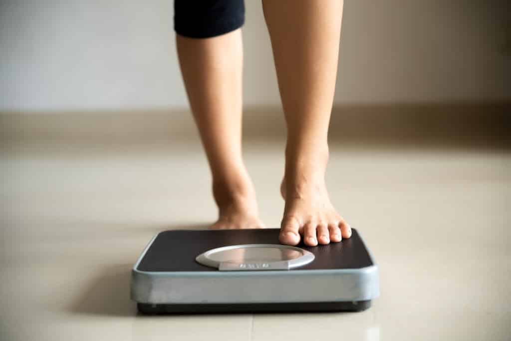 female leg stepping on weigh scales. healthy lifestyle food and sport concept. 1169486621 2122x1416